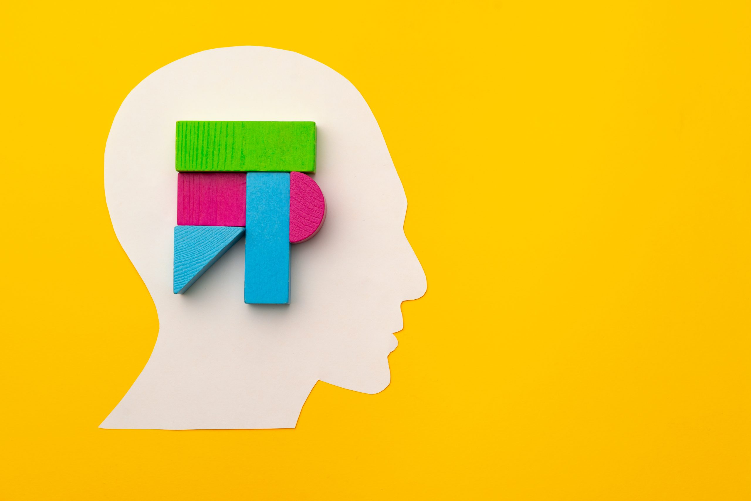 Papercut head silhouette with toy constructor pieces on yellow background